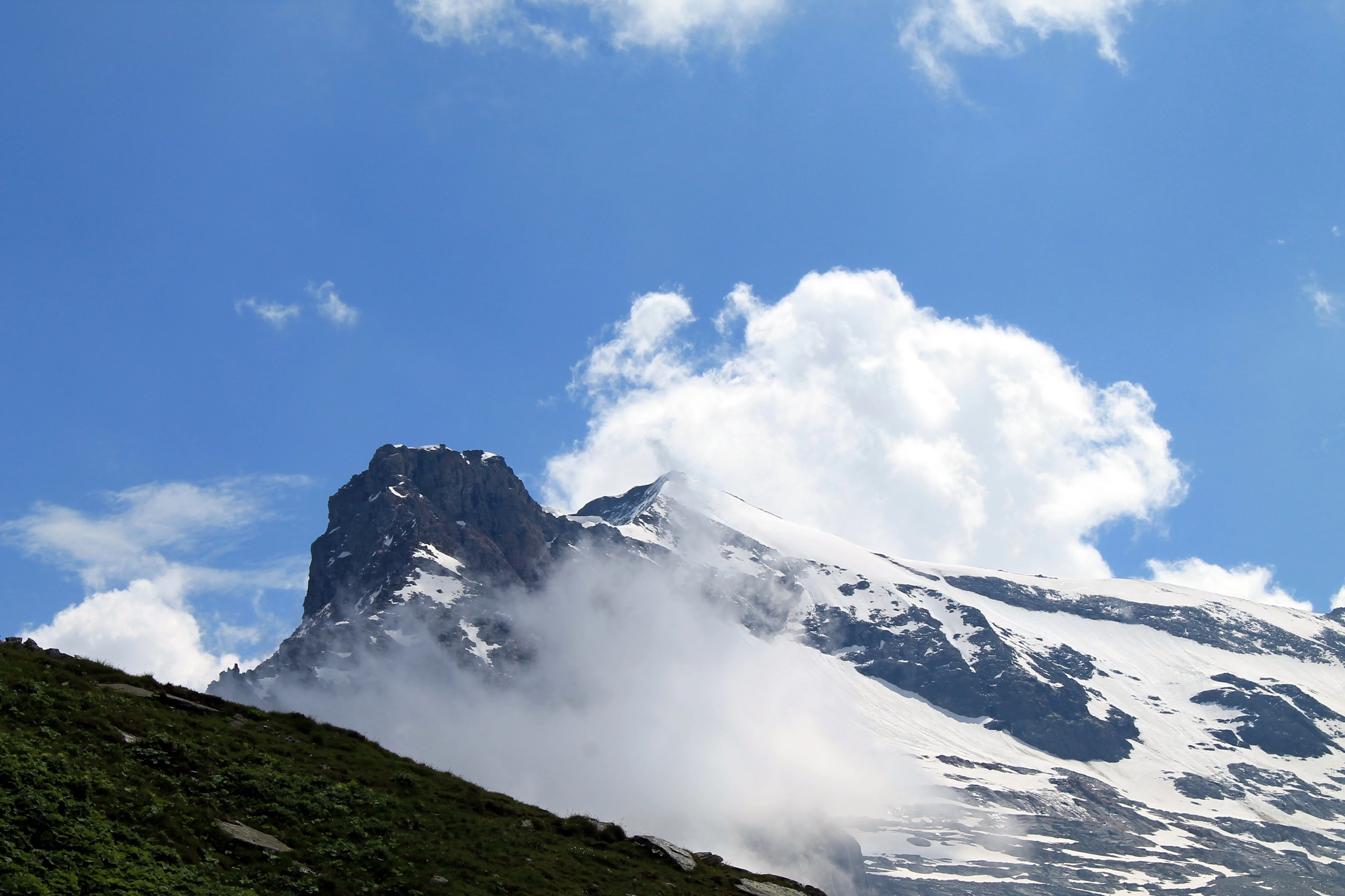 Temný skalní masiv s čepicí sněhu v nízké oblačnosti