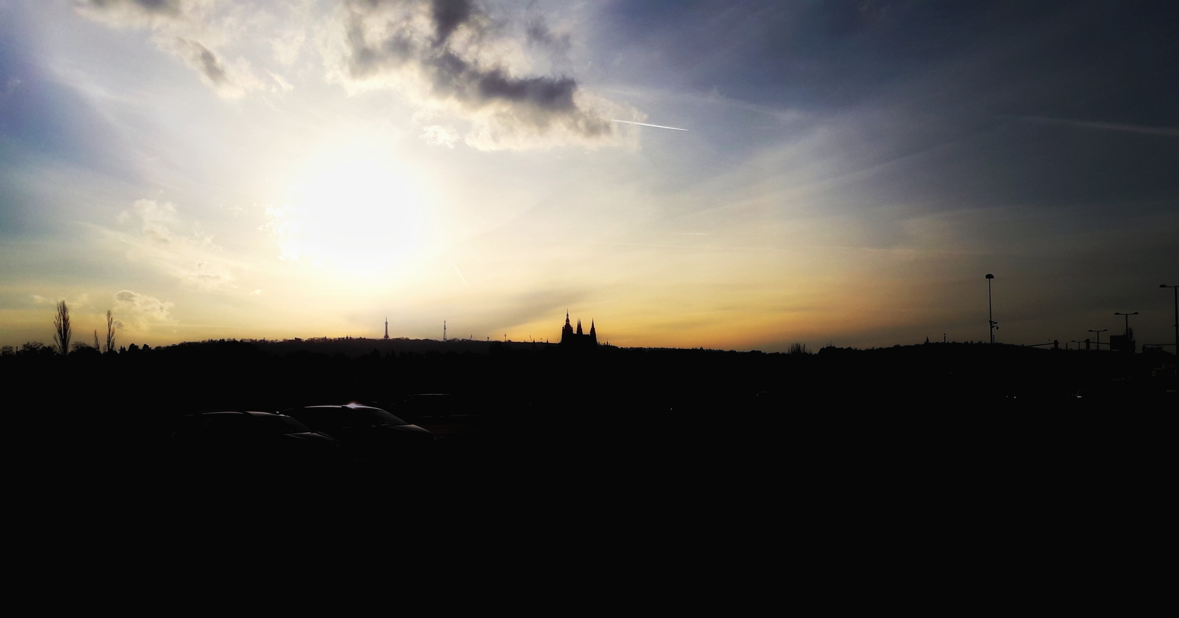 Silueta Pražského hradu proti zapadajícímu slunci na obzoru